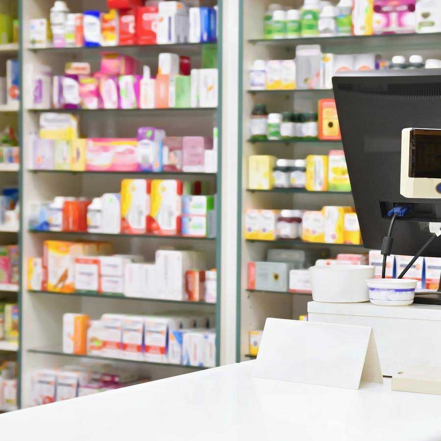 A pharmacy with lots of shelves and a computer on the counter.