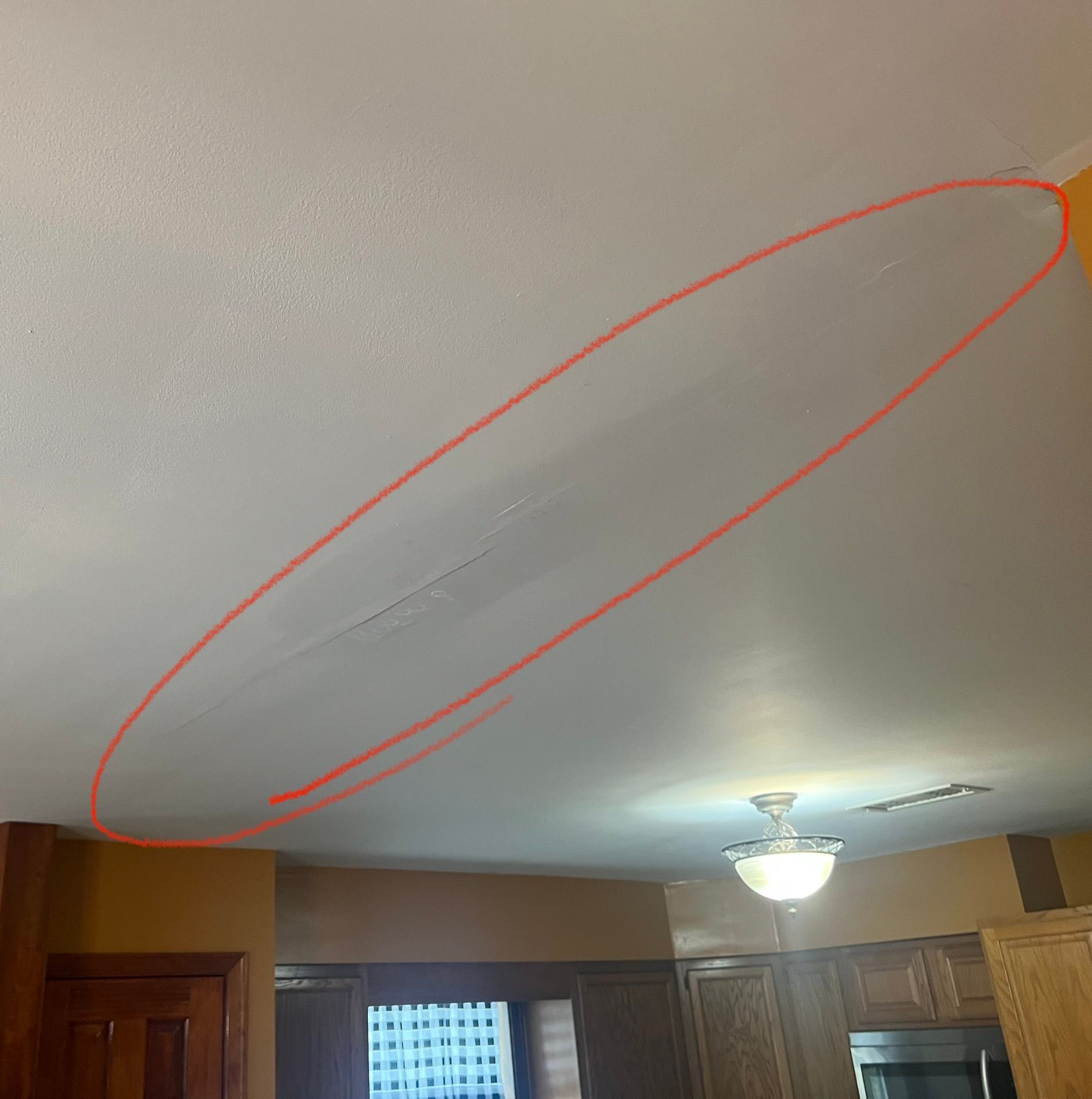 A white ceiling with water damage spots circled in red ink