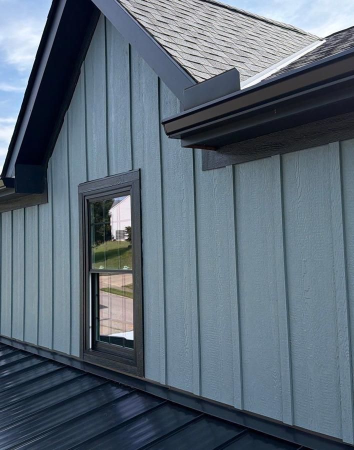 Blue-gray board and batten siding with dark trim and a new window on a Northern Kentucky home, finished by Fortress Solutions