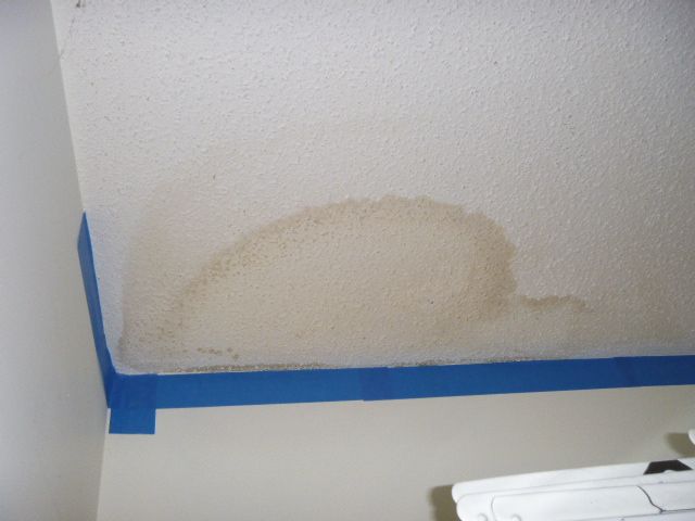 A water damaged ceiling with a blue tape around it