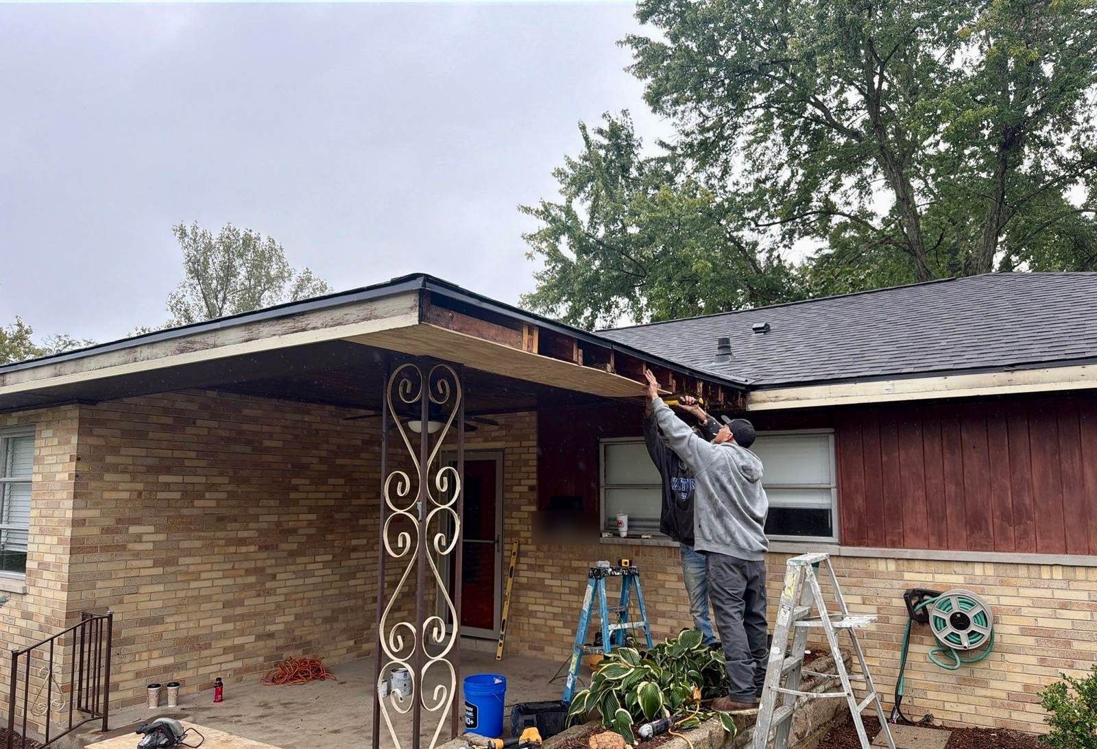 Two Fortress Solutions crew members replacing the soffit under a carport overhang on a brick ranch home