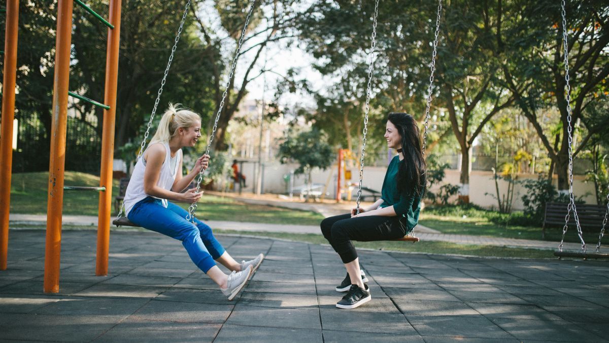 two woman sitting on a swing
