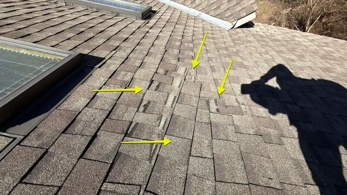 Arrows marking wind-damaged asphalt shingles on a Fruit Hill, Cincinnati roof