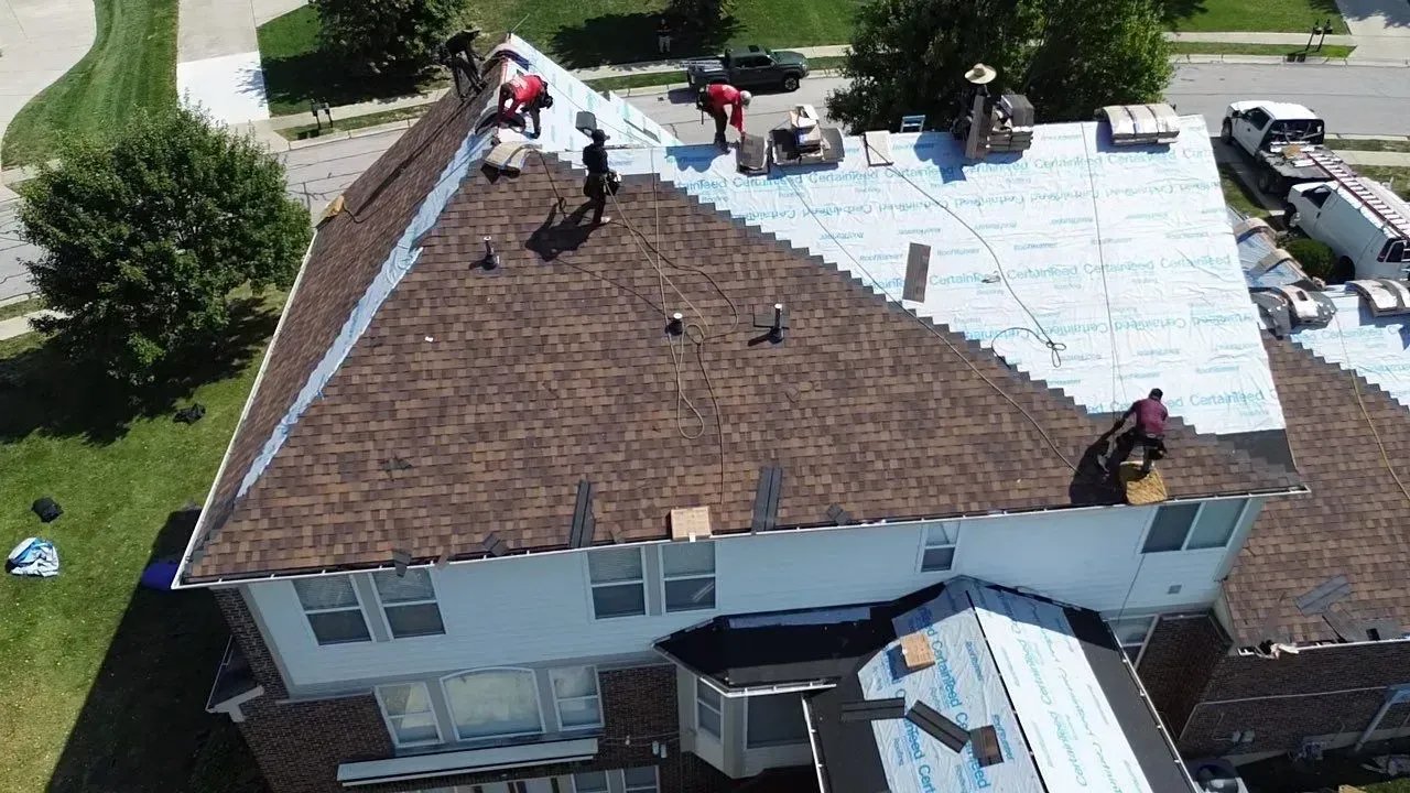 Drone view of synthetic underlayment going down as new shingles are installed
