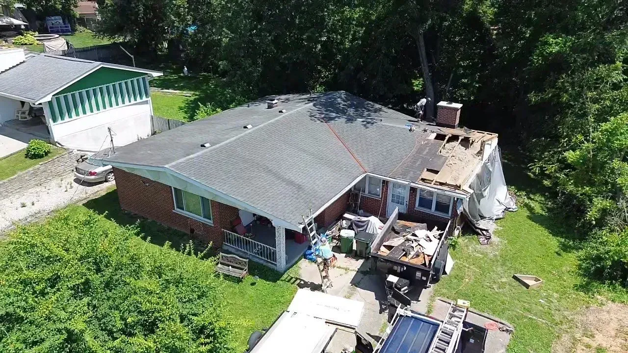 Drone view of roof tear-off and framing repairs on a Florence, KY ranch after a tree fell