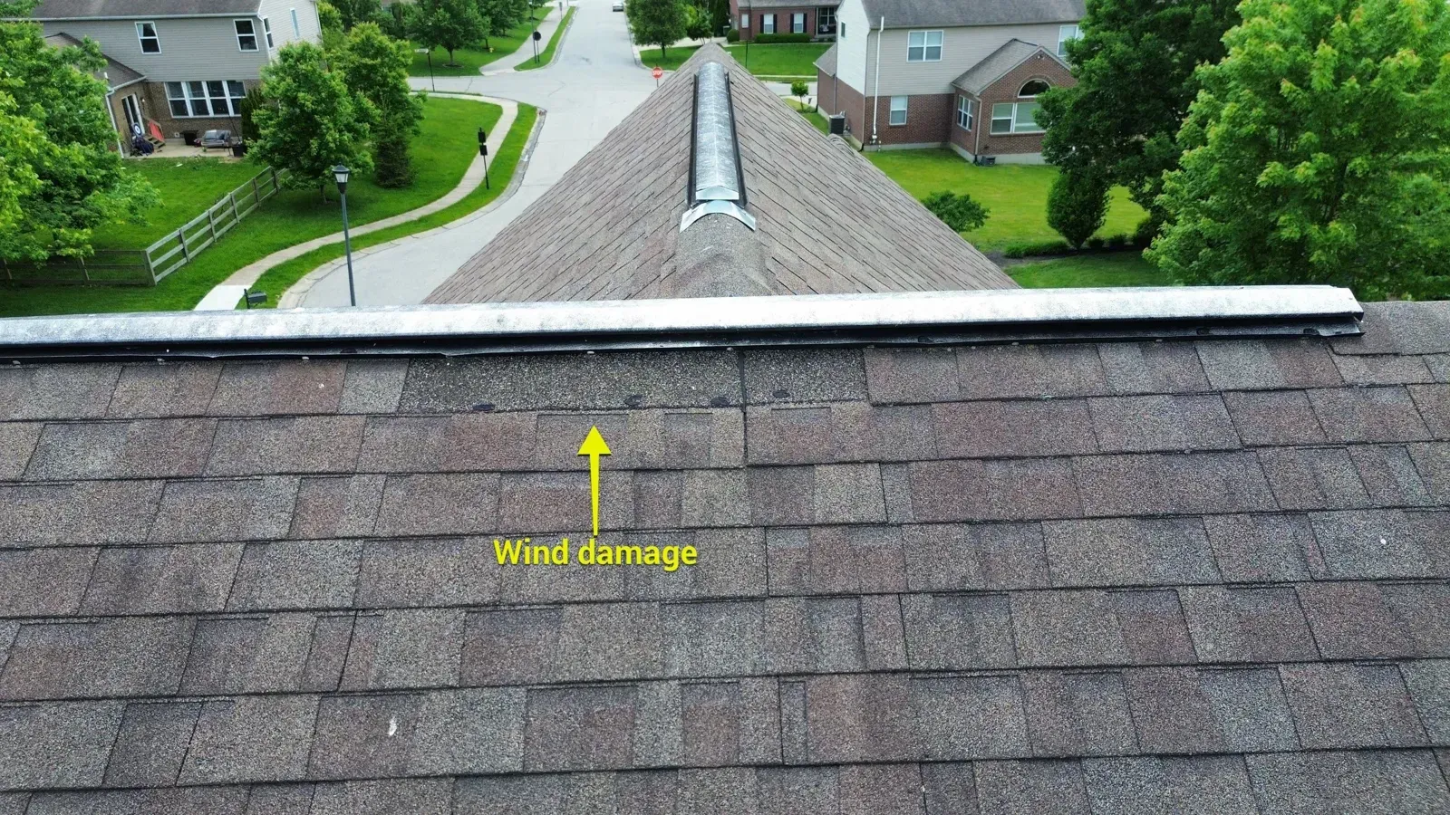 Marked wind damage on shingles below the ridge vent of a Florence, KY home