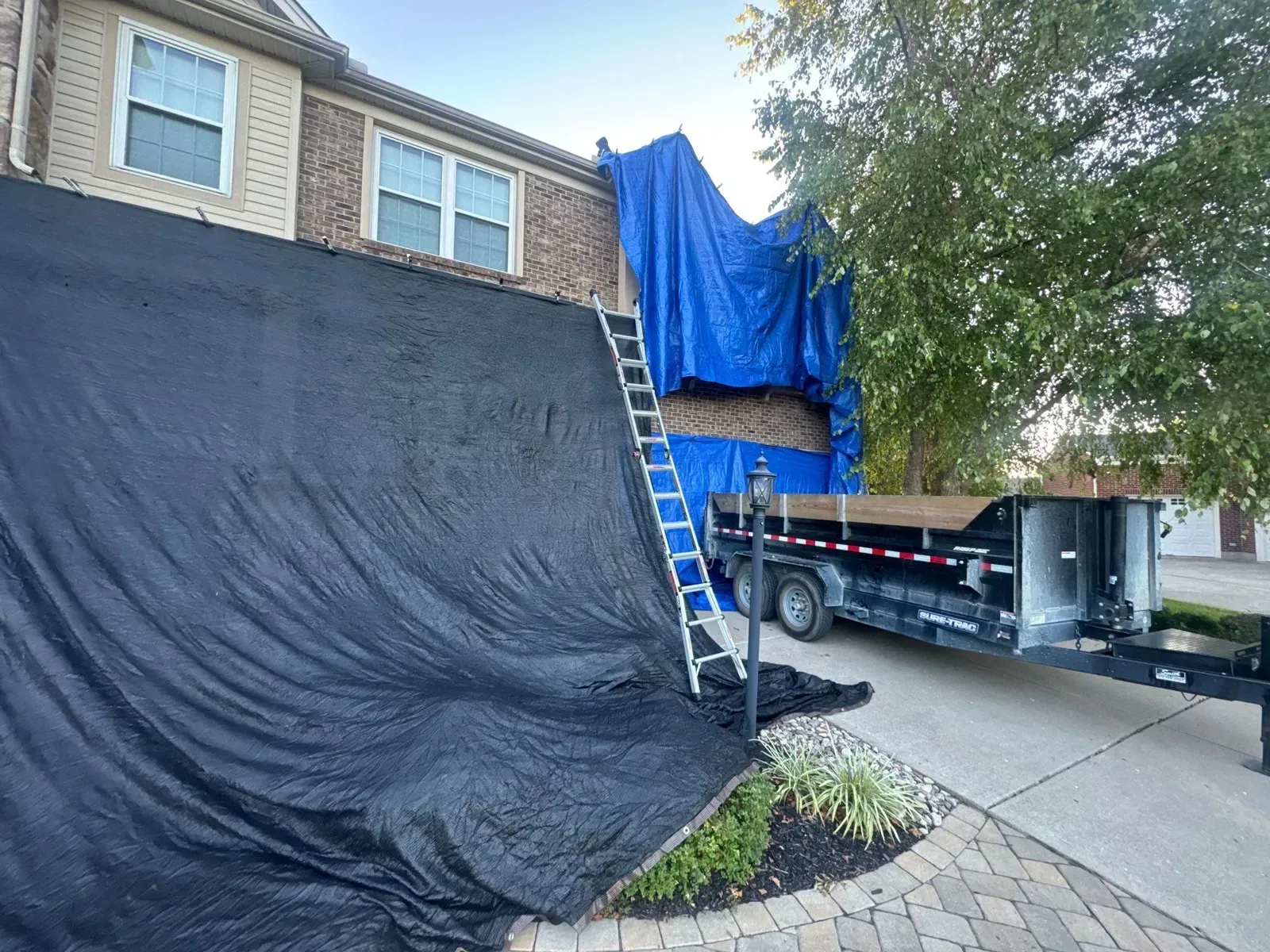 Tarps covering the siding and landscaping during a Florence, KY roof tear-off