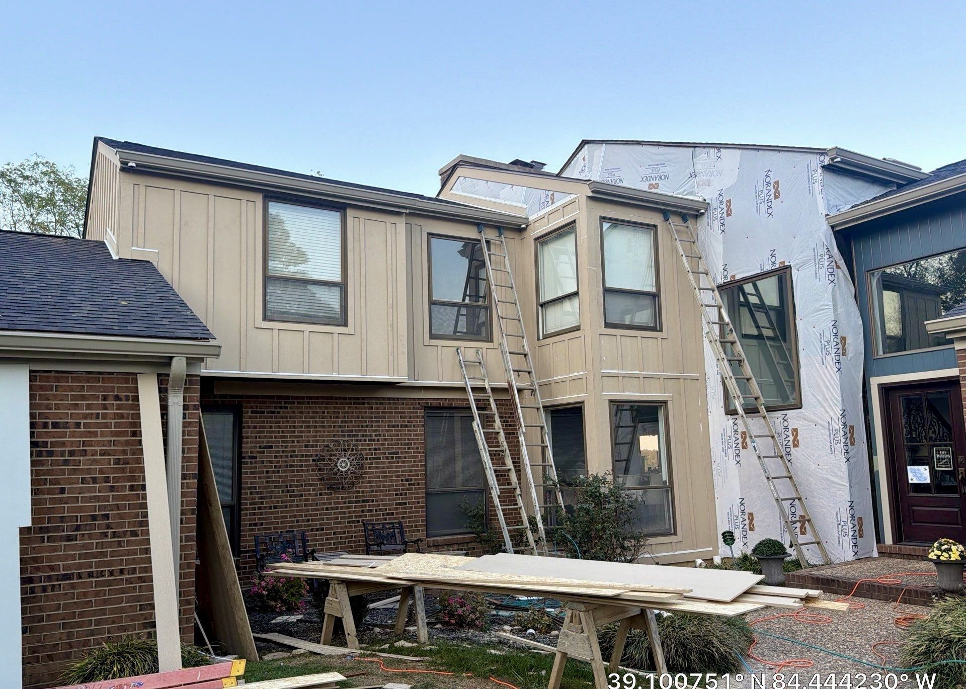 Ladders and workbench at a board and batten siding job with Norandex house wrap on the wall