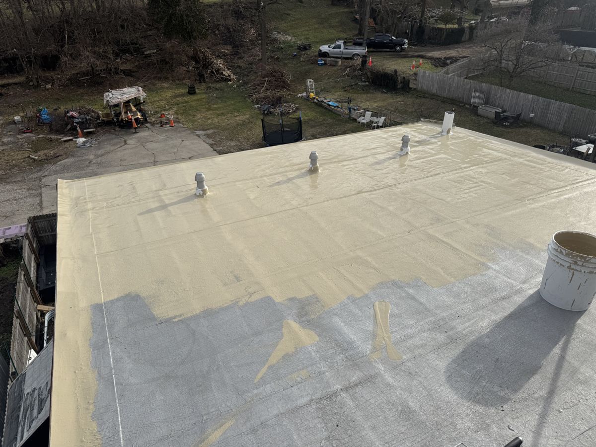 Tan silicone coating halfway across a residential flat roof