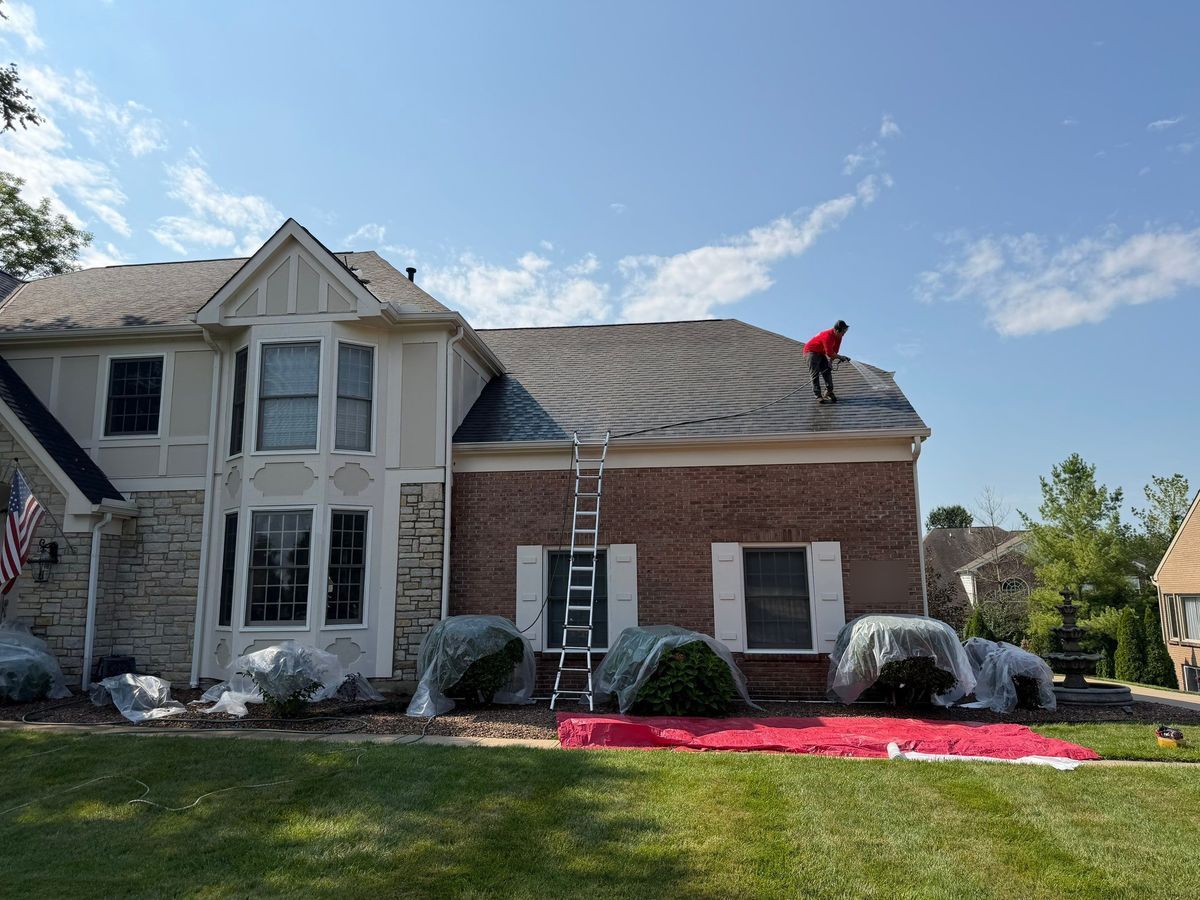 Shrubs covered in plastic and red tarp laid out before roof soft washing