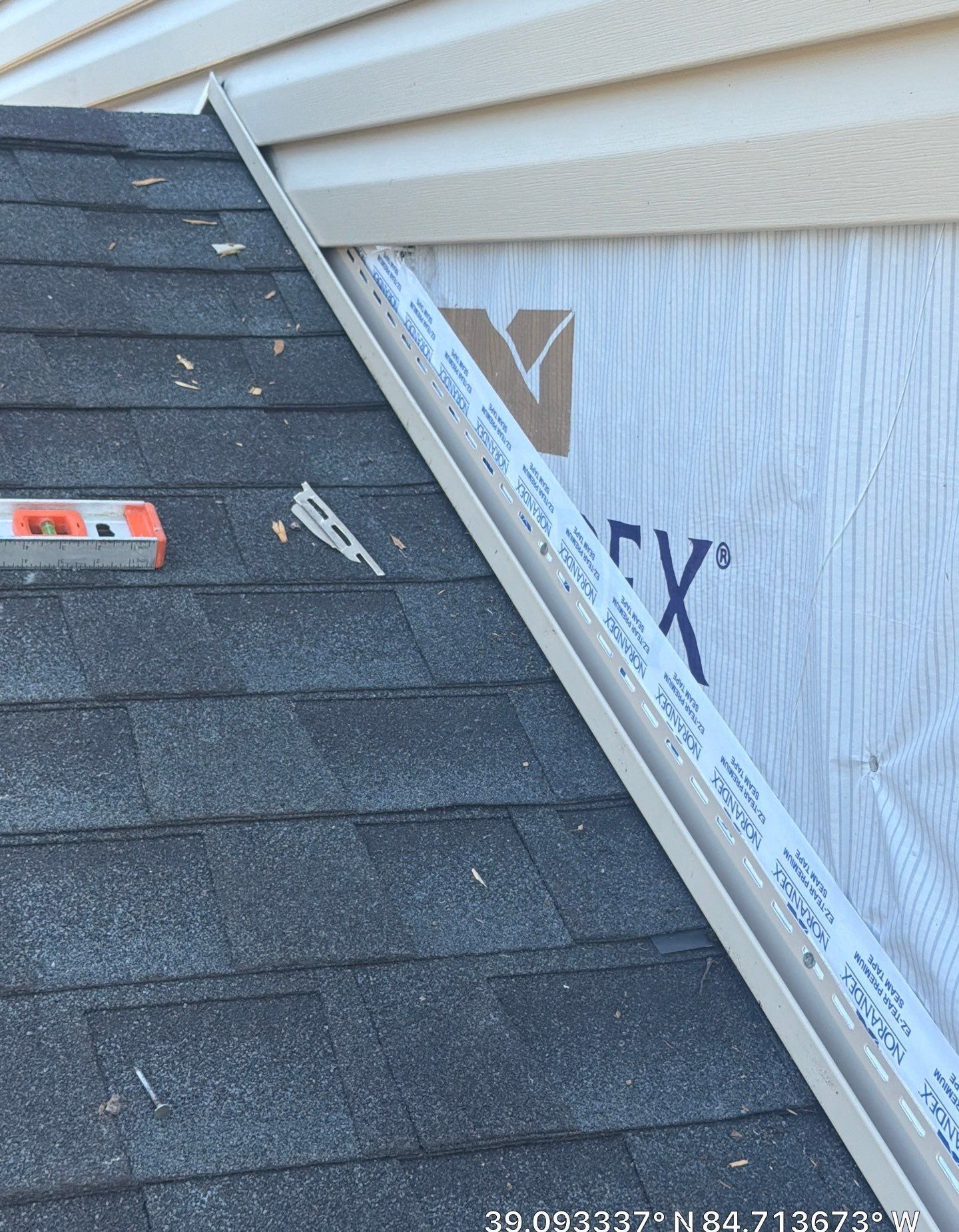 Siding installation at a roof-to-wall joint with J-channel and seam tape on the house wrap