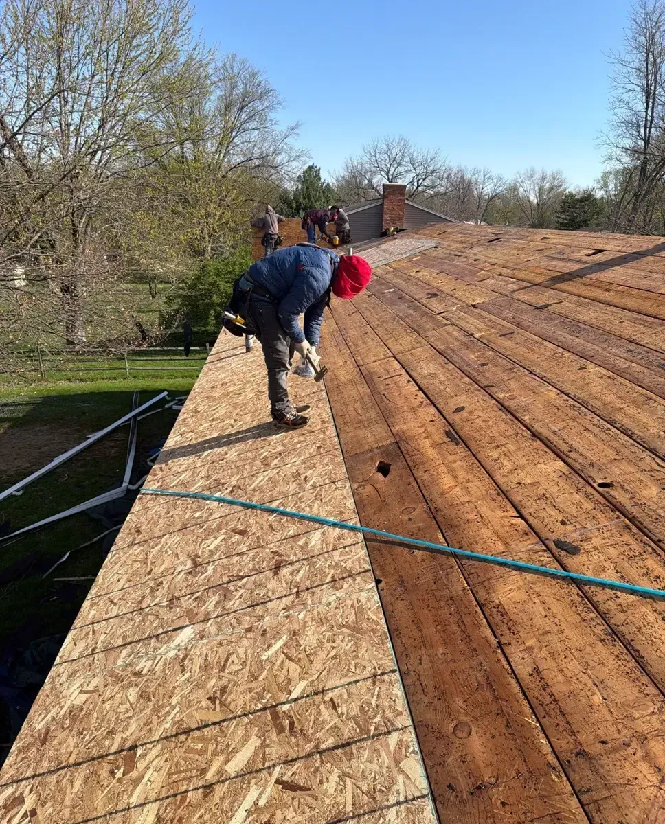 Roofers installing new OSB sheathing over old spaced boards