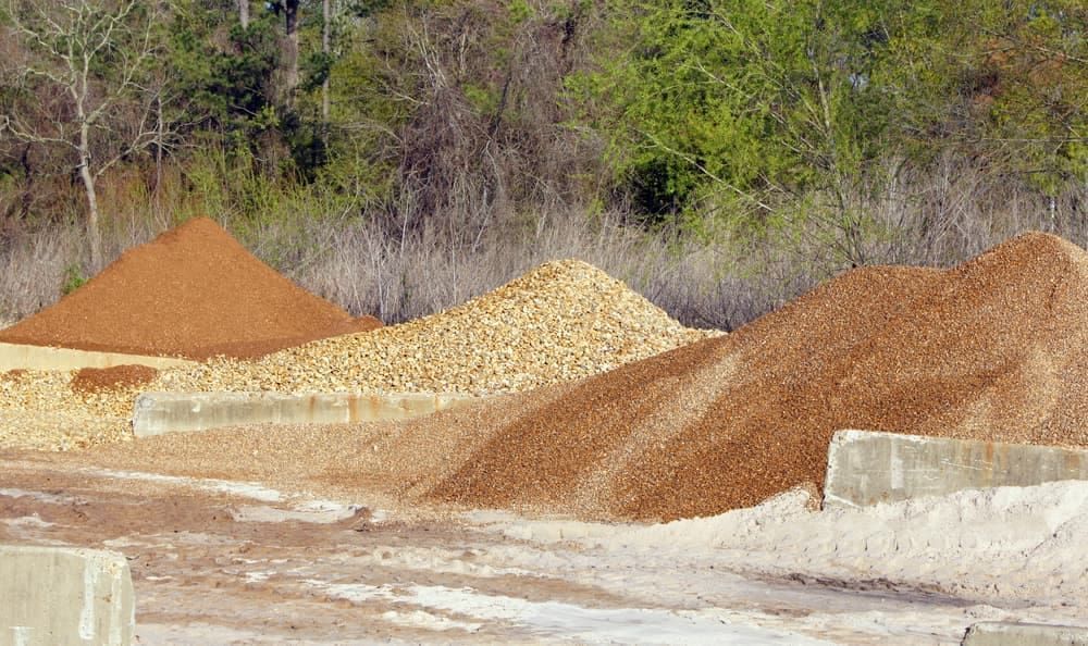 Piles of Gravel in Various Shades of Brown and Tan, in Front of a Tree Line — The Soil Yard in Delacombe, VIC