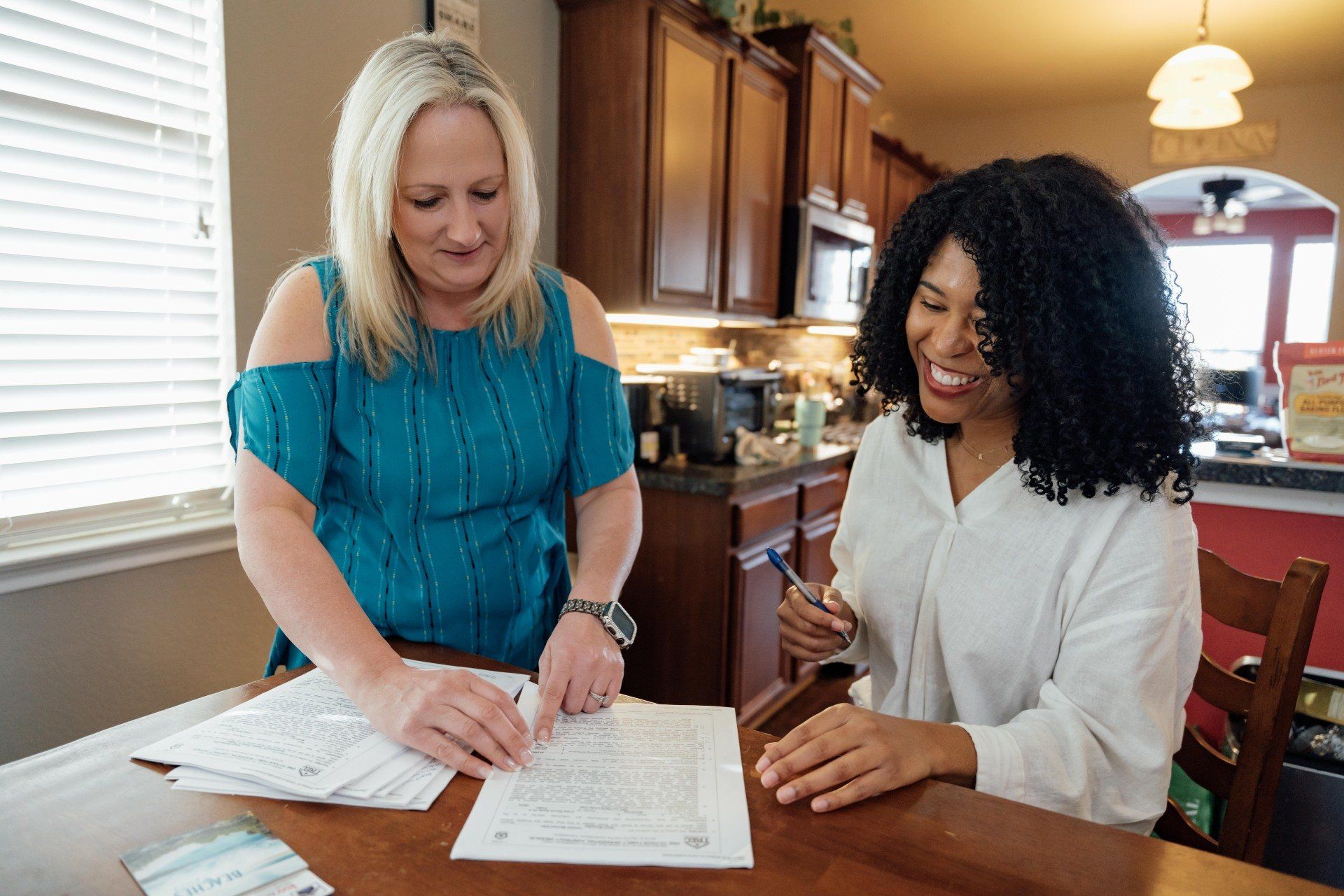 Two women are sitting at a table looking at papers.