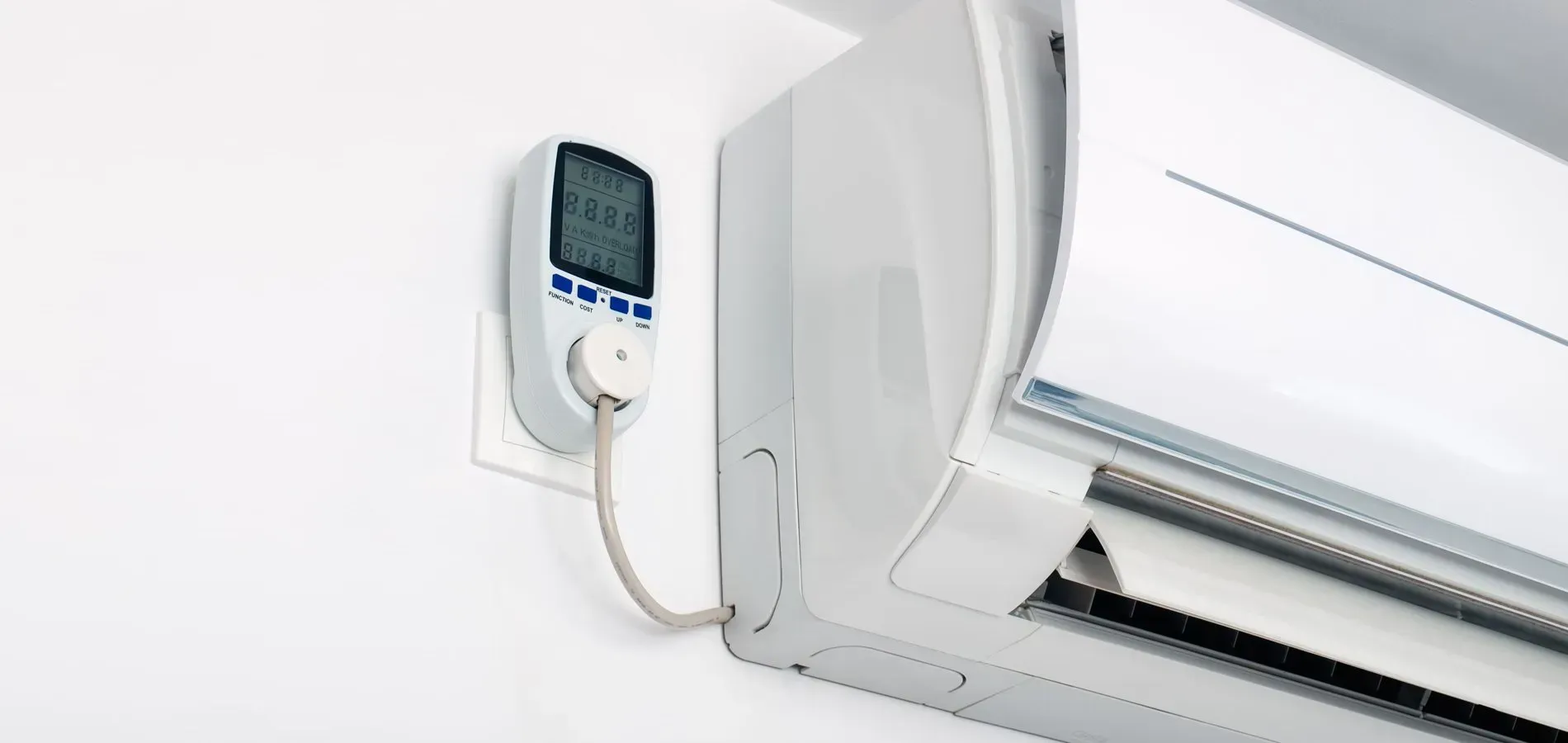 Wall-mounted air conditioner with a small wired control unit on a white wall