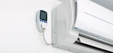 Wall-mounted air conditioner with a remote control on the wall beside it