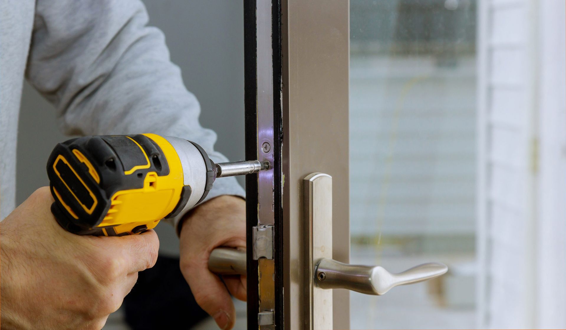 A Man Is Fixing a Door with A Drill | Bundaberg, QLD | Wide Bay Architectural Hardware
