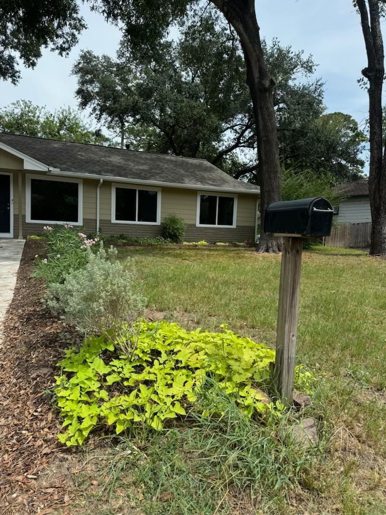 Beige house with a mailbox, front yard garden with bright green vines.