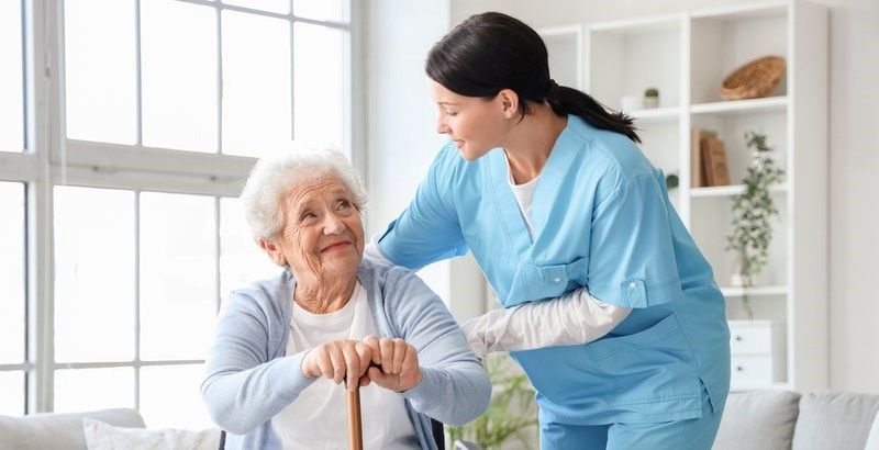 A nurse is helping an elderly woman with a cane.