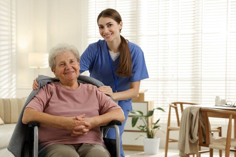 A nurse is standing next to an elderly woman in a wheelchair.