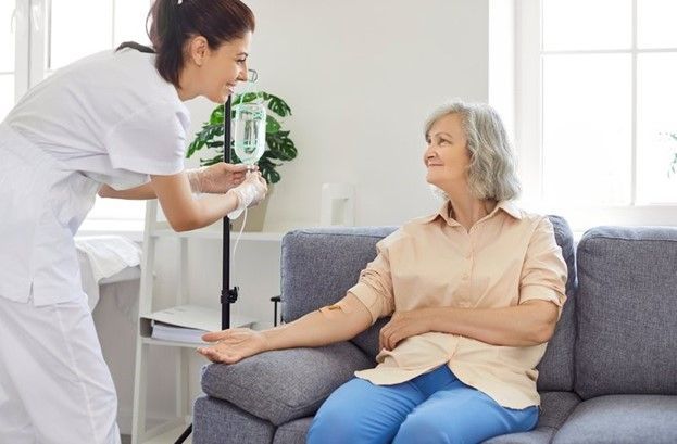 An Elderly Woman Is Sitting on A Couch Getting an Injection from A Nurse An Elderly Woman Is Sitting on A Couch Getting an Injection from A Nurse