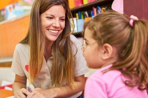 Woman and young boy playing with building blocks at a table in a classroom
