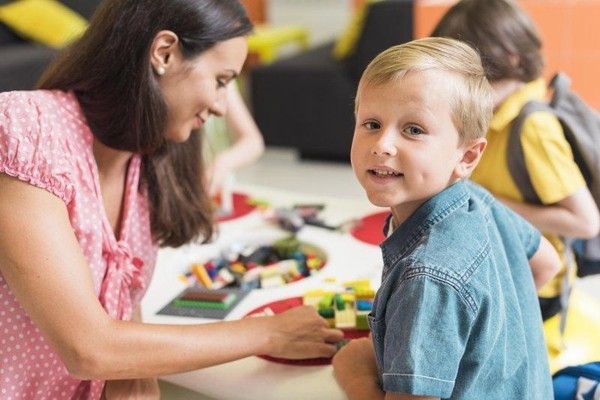 Woman and young boy playing with building blocks at a table in a classroom