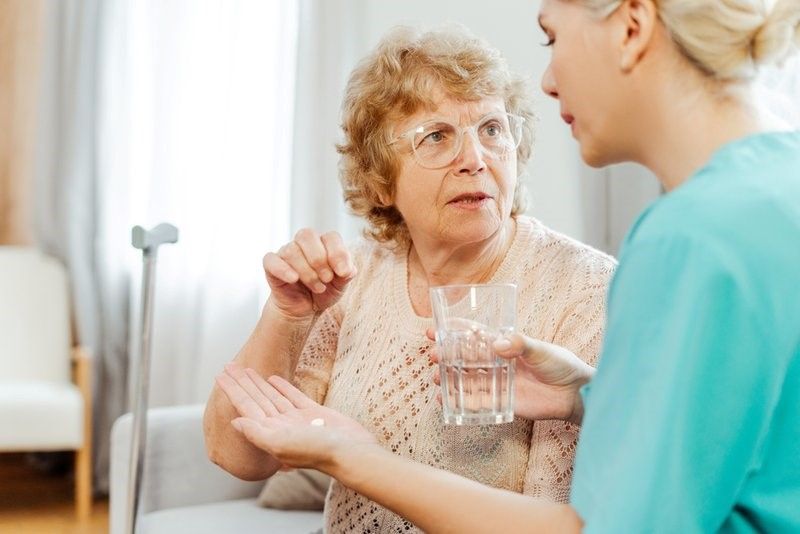 A Nurse Is Giving an Elderly Woman a Pill and A Glass of Water. A Nurse Is Giving an Elderly Woman a Pill and A Glass of Water.