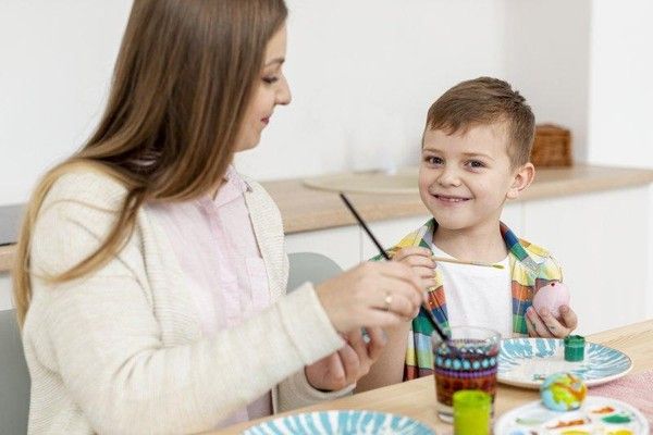 Woman and young boy playing with building blocks at a table in a classroom