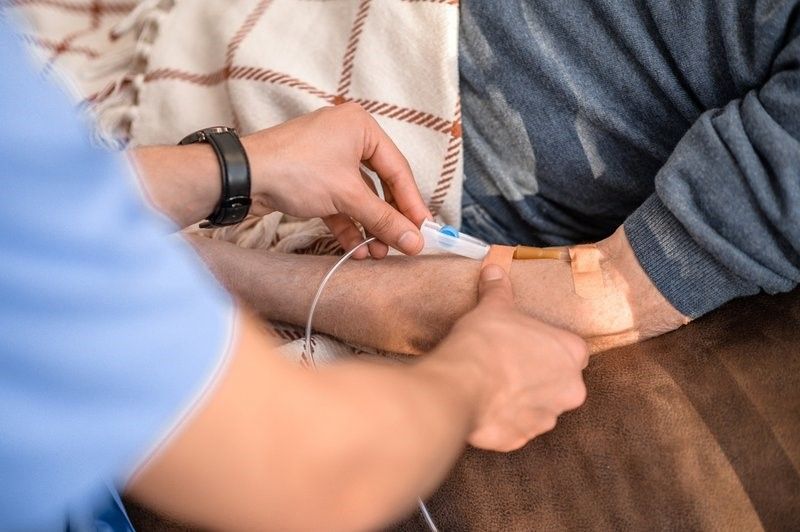 A nurse is putting an iv into a patient 's arm. A nurse is putting an iv into a patient 's arm.