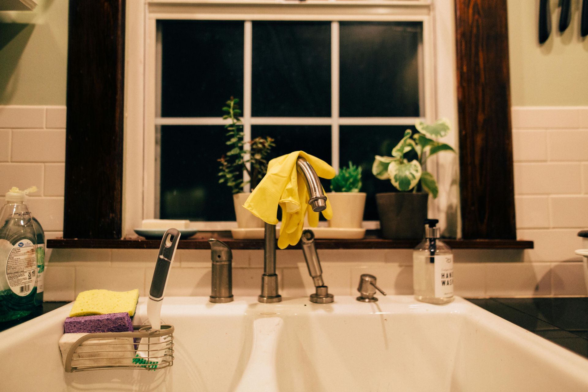 A kitchen sink with a yellow cloth on the faucet