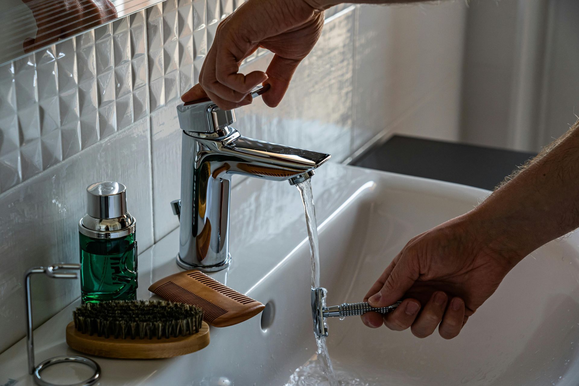 A person is shaving their beard in a bathroom sink