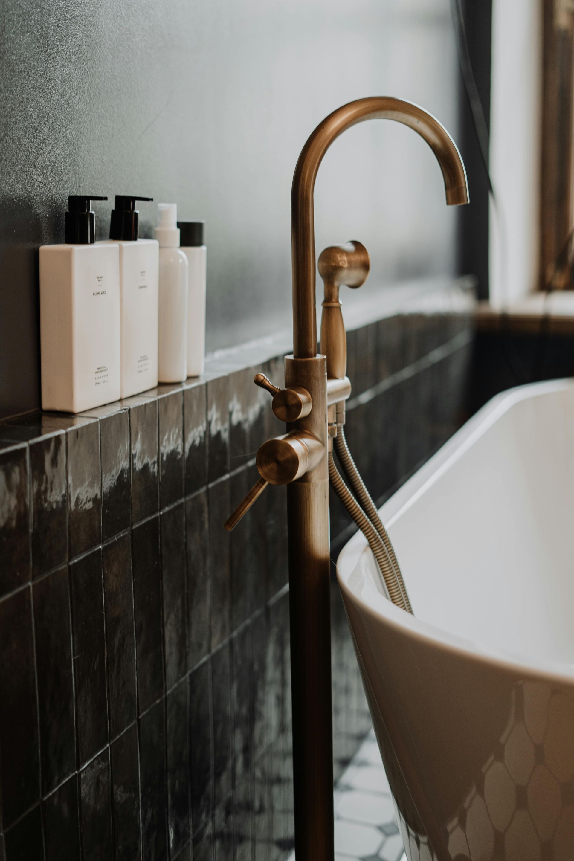 A bathroom with a bathtub and a brass faucet