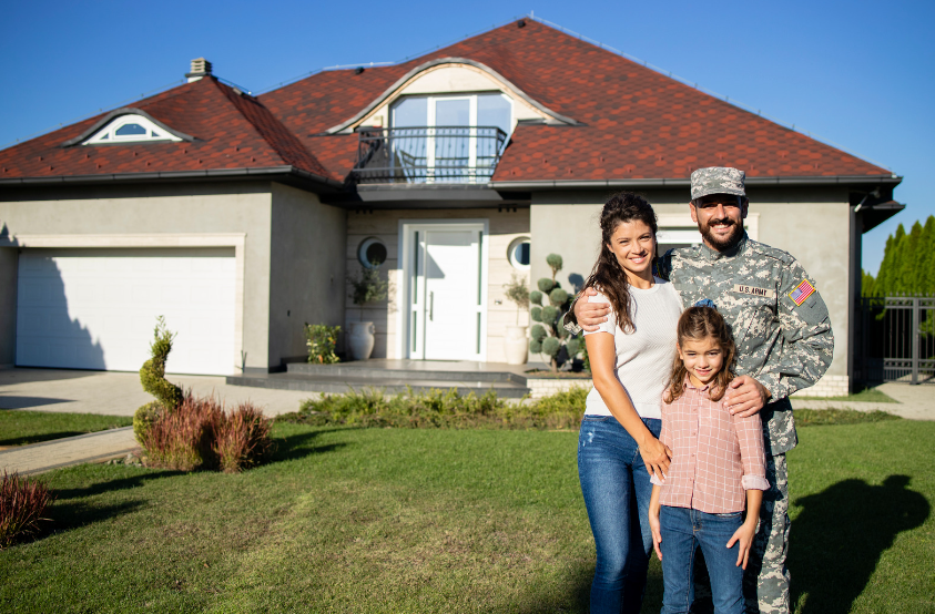 A soldier and his family are standing in front of their new home.