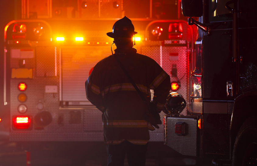 A fireman is standing in front of a fire truck.