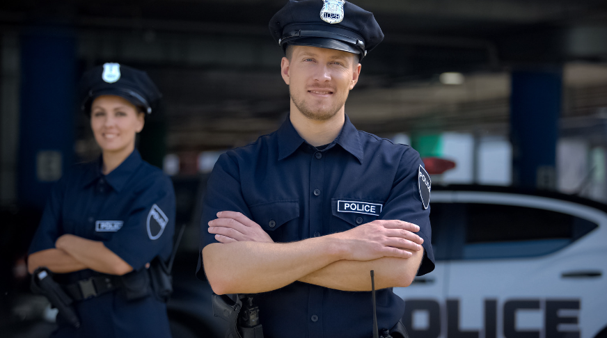 A man and a woman are standing next to each other in front of a police car.