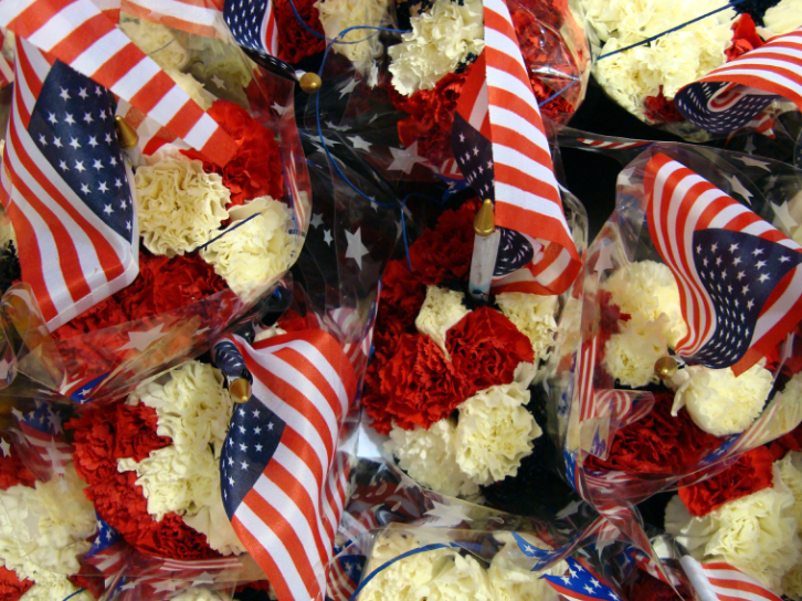 A bunch of red white and blue flowers with american flags