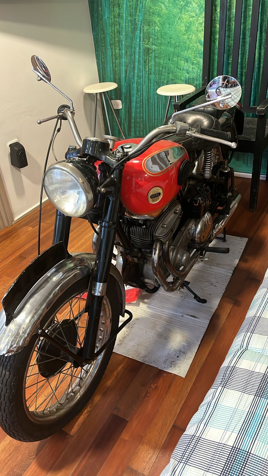 Motocicleta vintage roja y negra en interiores con fondo verde y blanco.