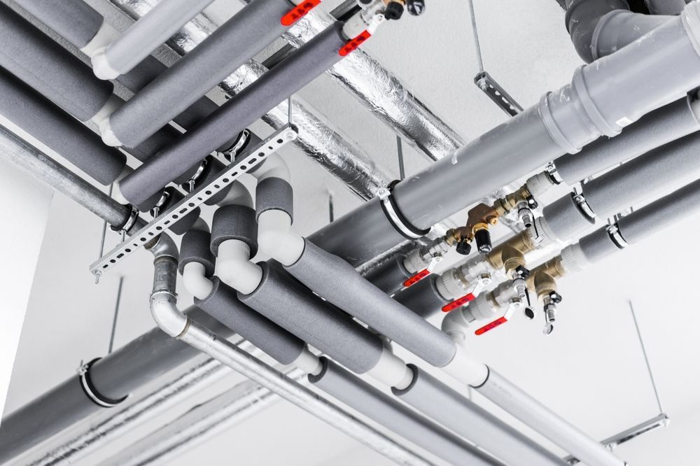 A Bunch of Pipes Are Hanging From the Ceiling of a Building — Mainline Plumbing & Civil Pty Ltd In Bathurst, NSW