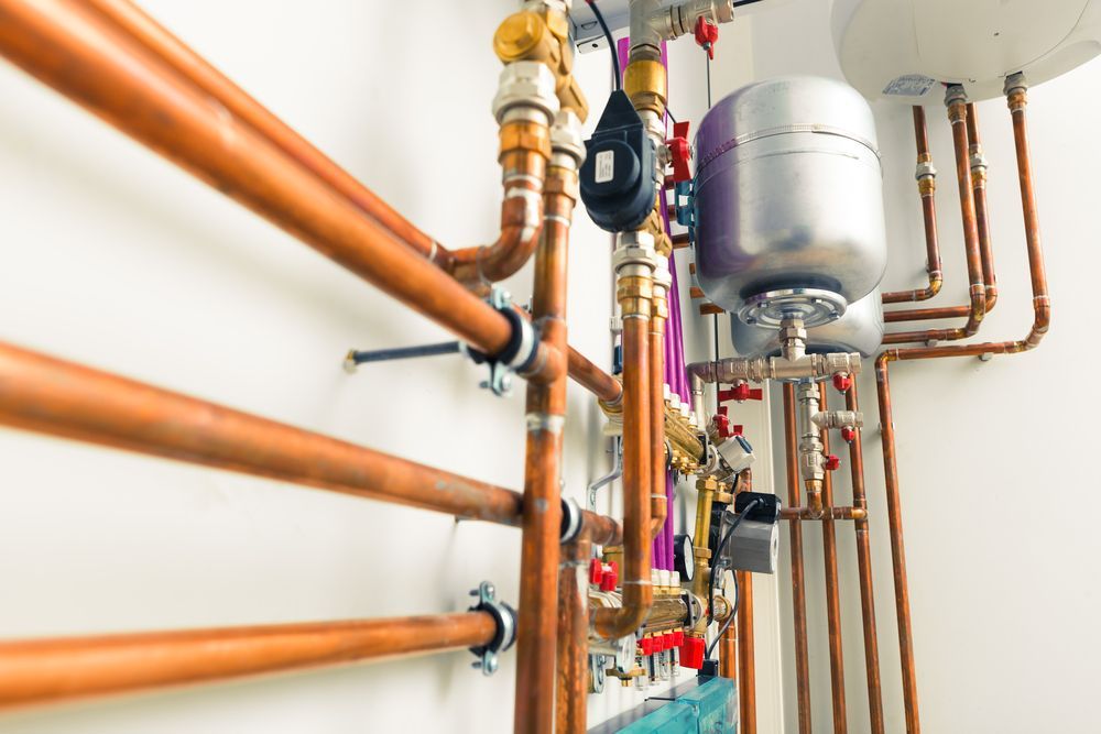 a Row of Copper Pipes Hanging on a Wall in a Room — Mainline Plumbing & Civil Pty Ltd In Brewarrina, NSW