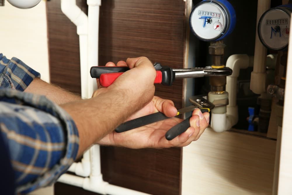 Plumber's Hands Using Wrenches to Repair Pipes — Mainline Plumbing & Civil Pty Ltd In Dubbo, NSW