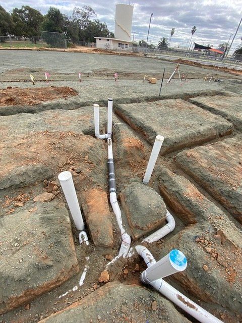 A Bunch of Pipes Are Laying in the Dirt on a Construction Site — Mainline Plumbing & Civil Pty Ltd In Dubbo, NSW