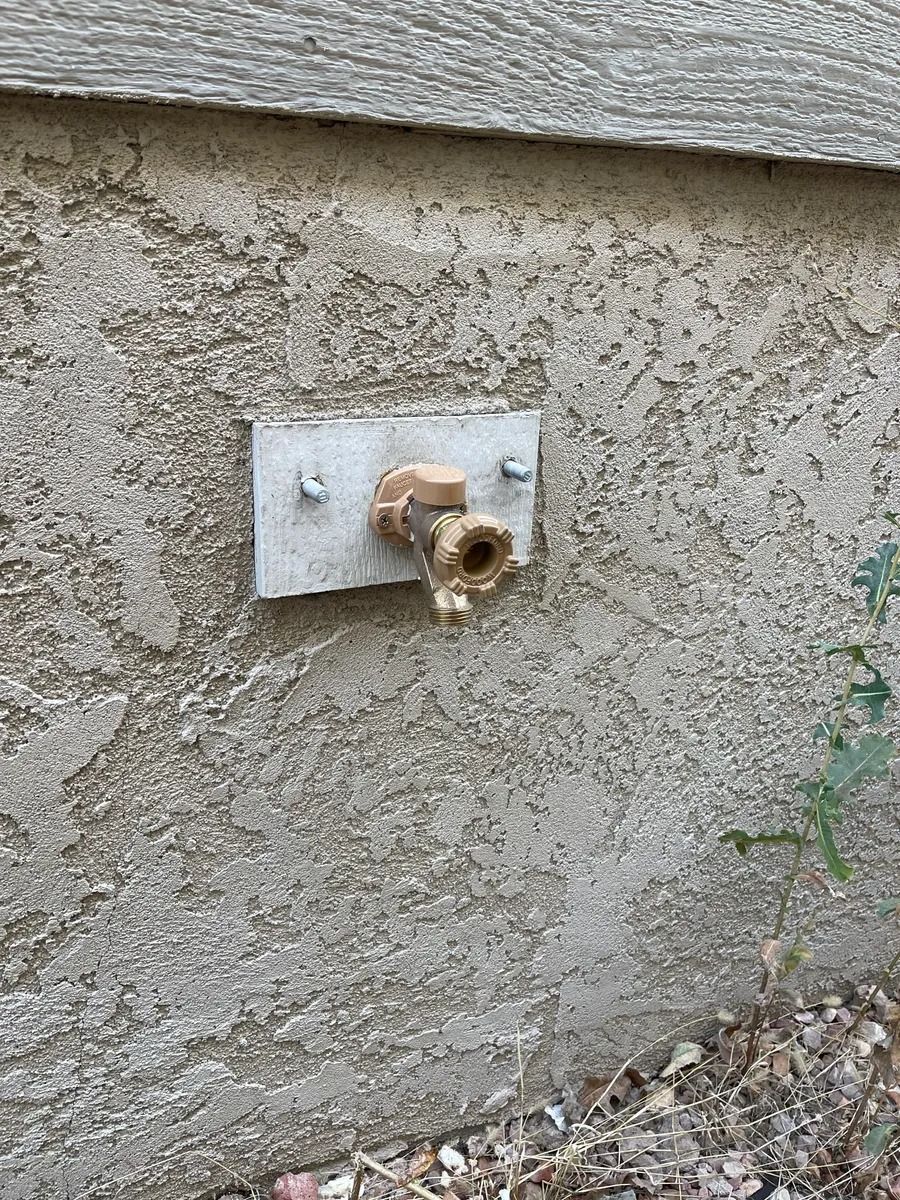 Rusty outdoor water spigot mounted on a concrete wall with peeling paint.