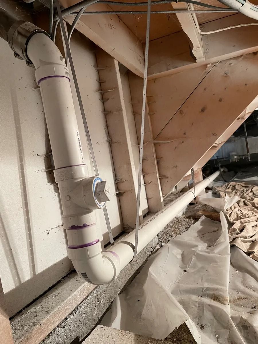 Industrial basement with white pipes and debris under slanted wooden beams