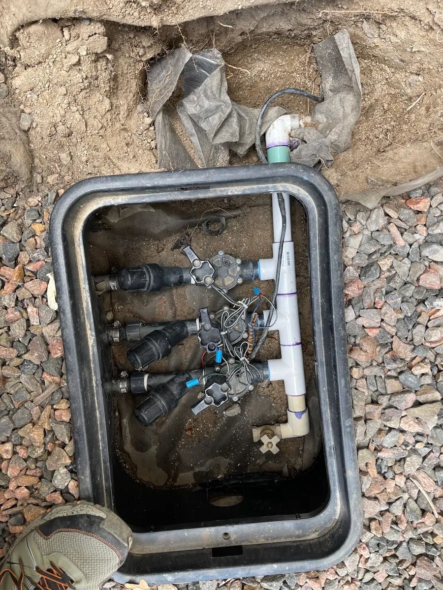 Open utility meter box with exposed valves and pipes in the ground