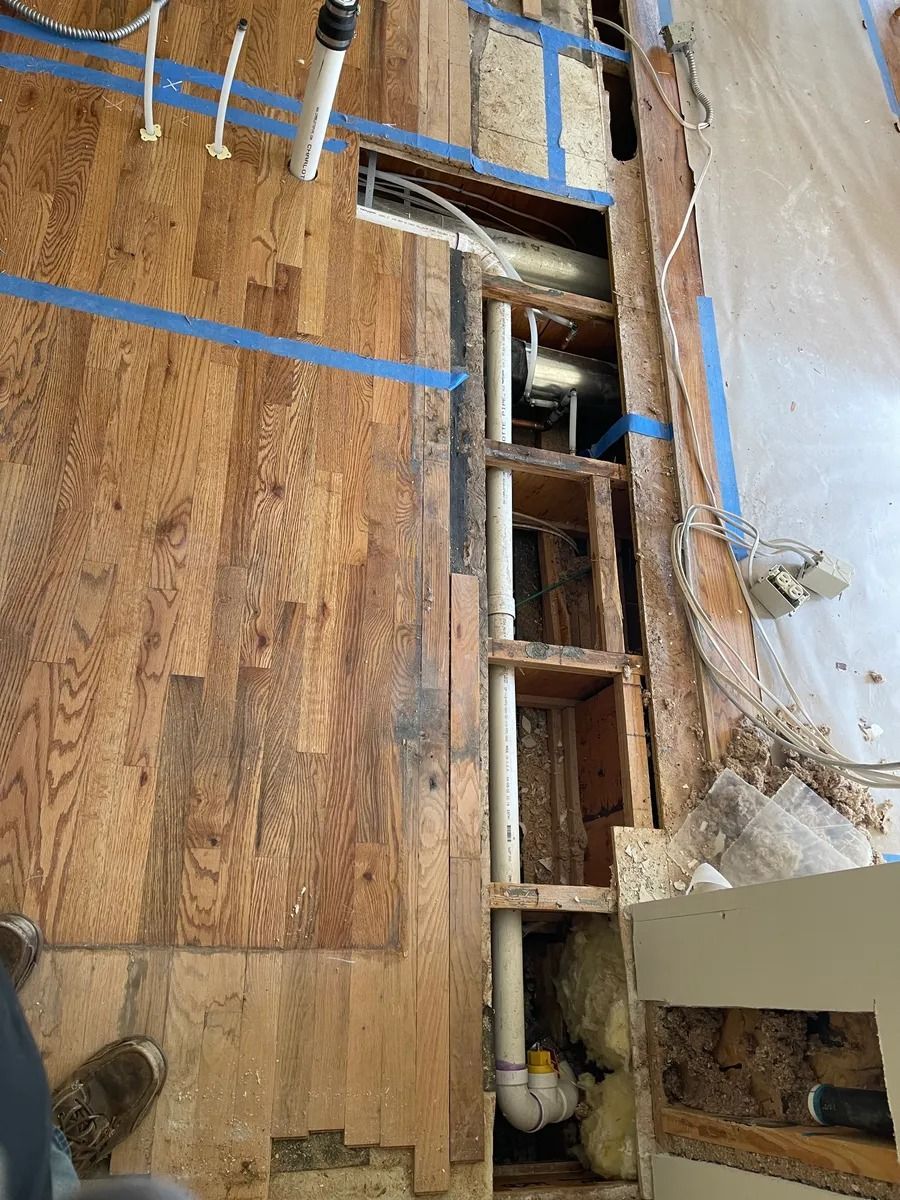 Exposed wall studs and plywood with blue tape in a damaged interior under renovation
