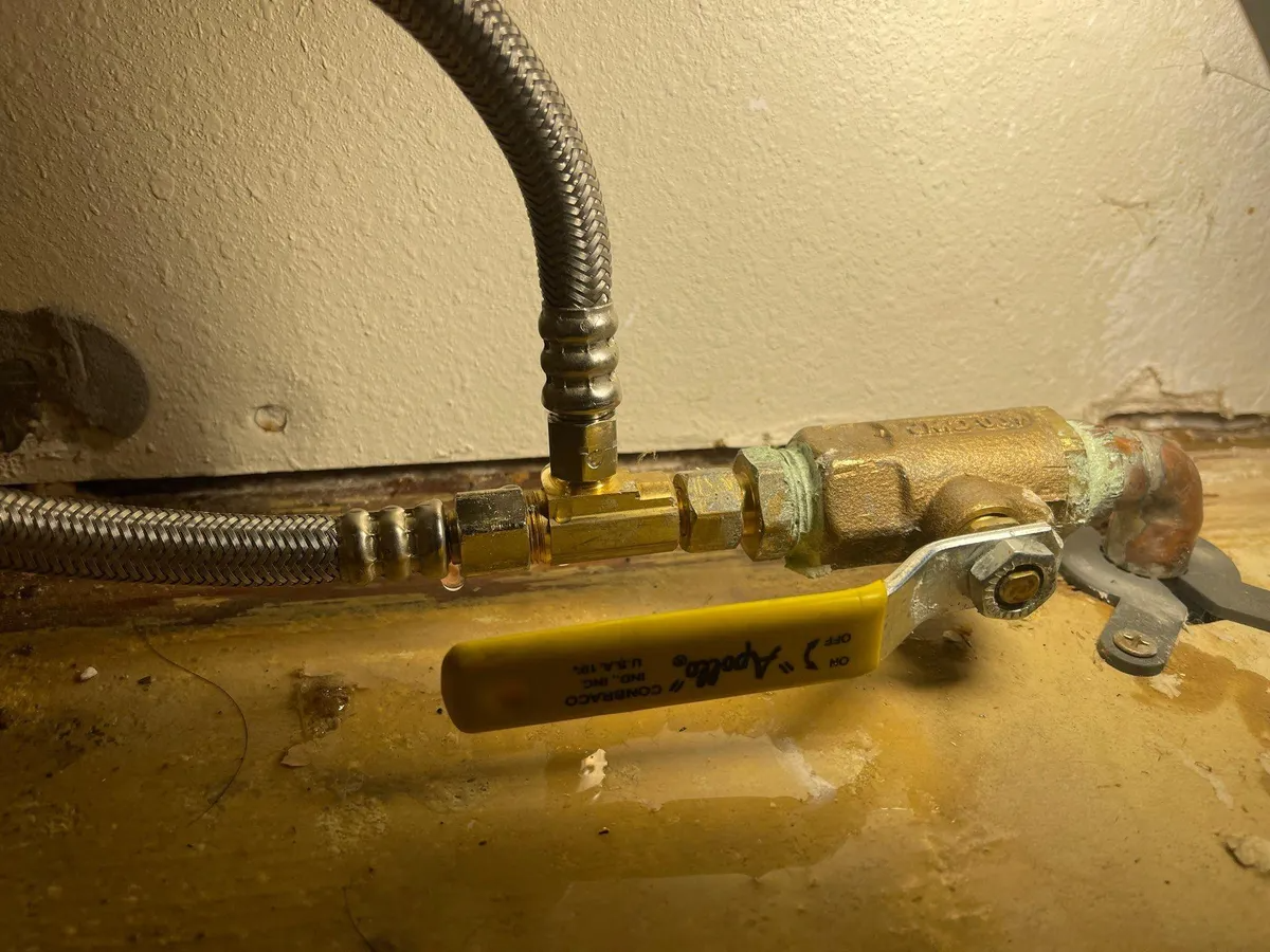 Close-up of a brass valve and flexible hoses on a yellow gas cylinder.