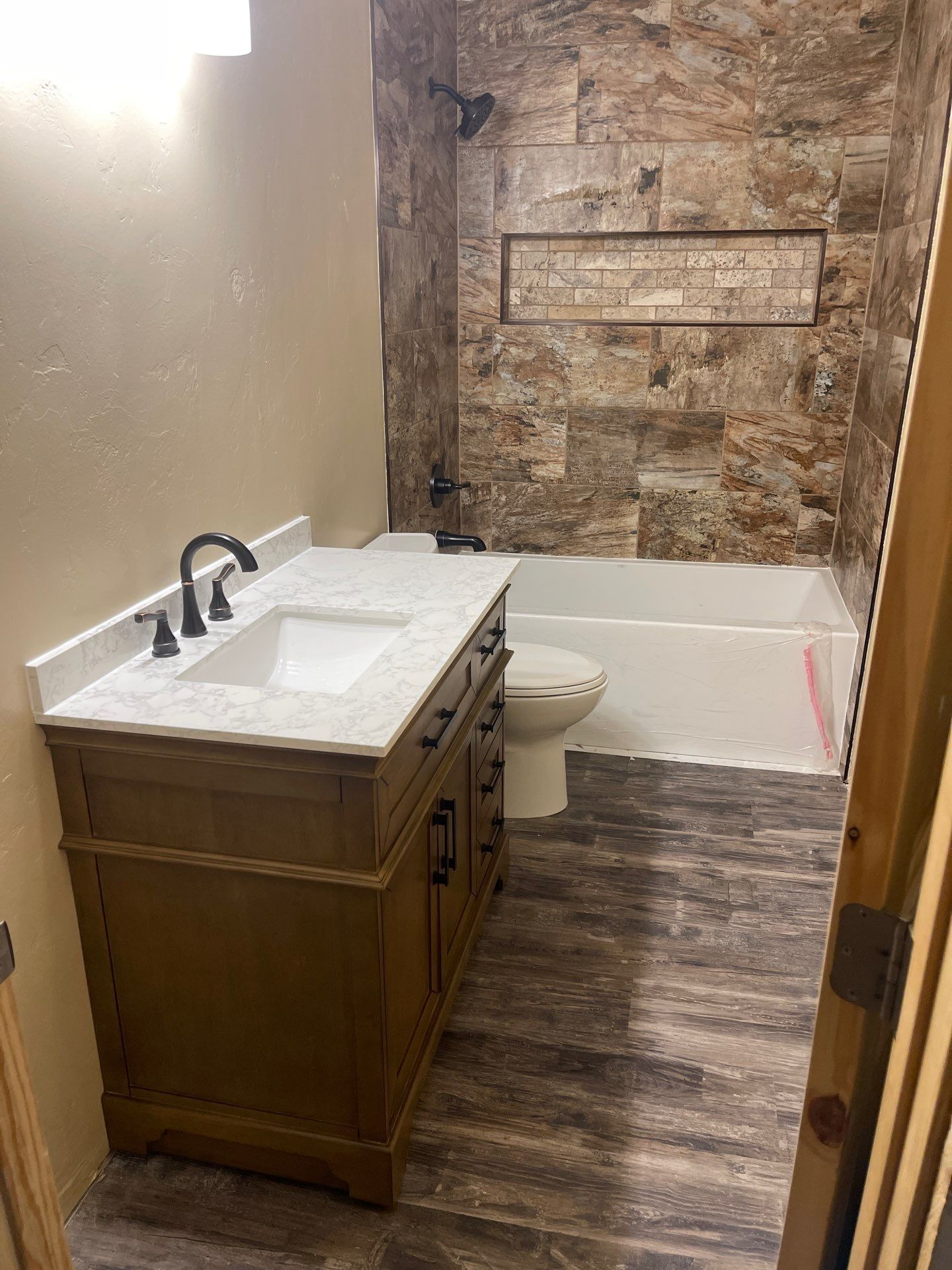 Small bathroom with vanity sink, toilet, tub, and rustic stone accent wall.
