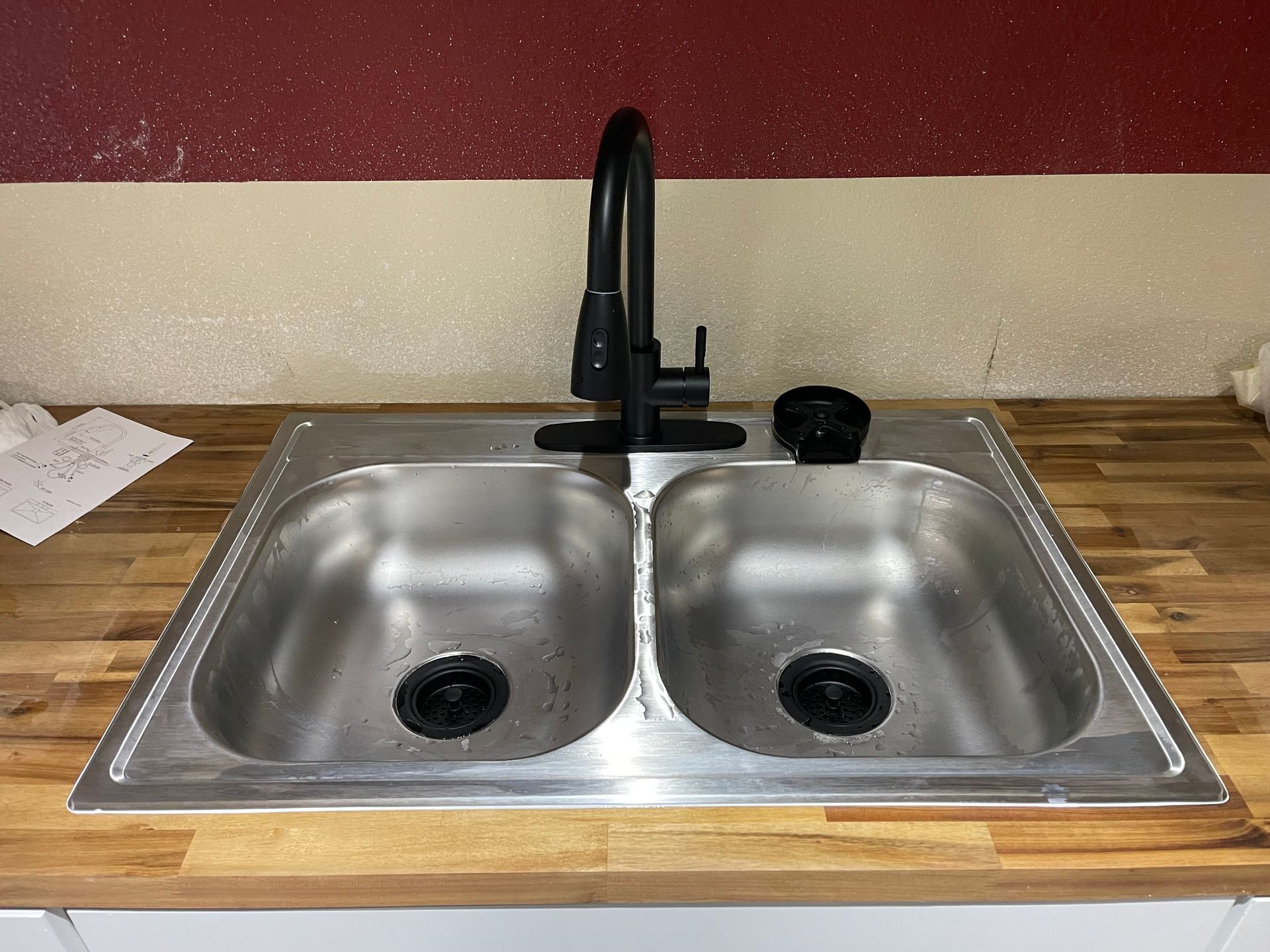 Double-basin stainless steel kitchen sink with matte black faucet on a countertop
