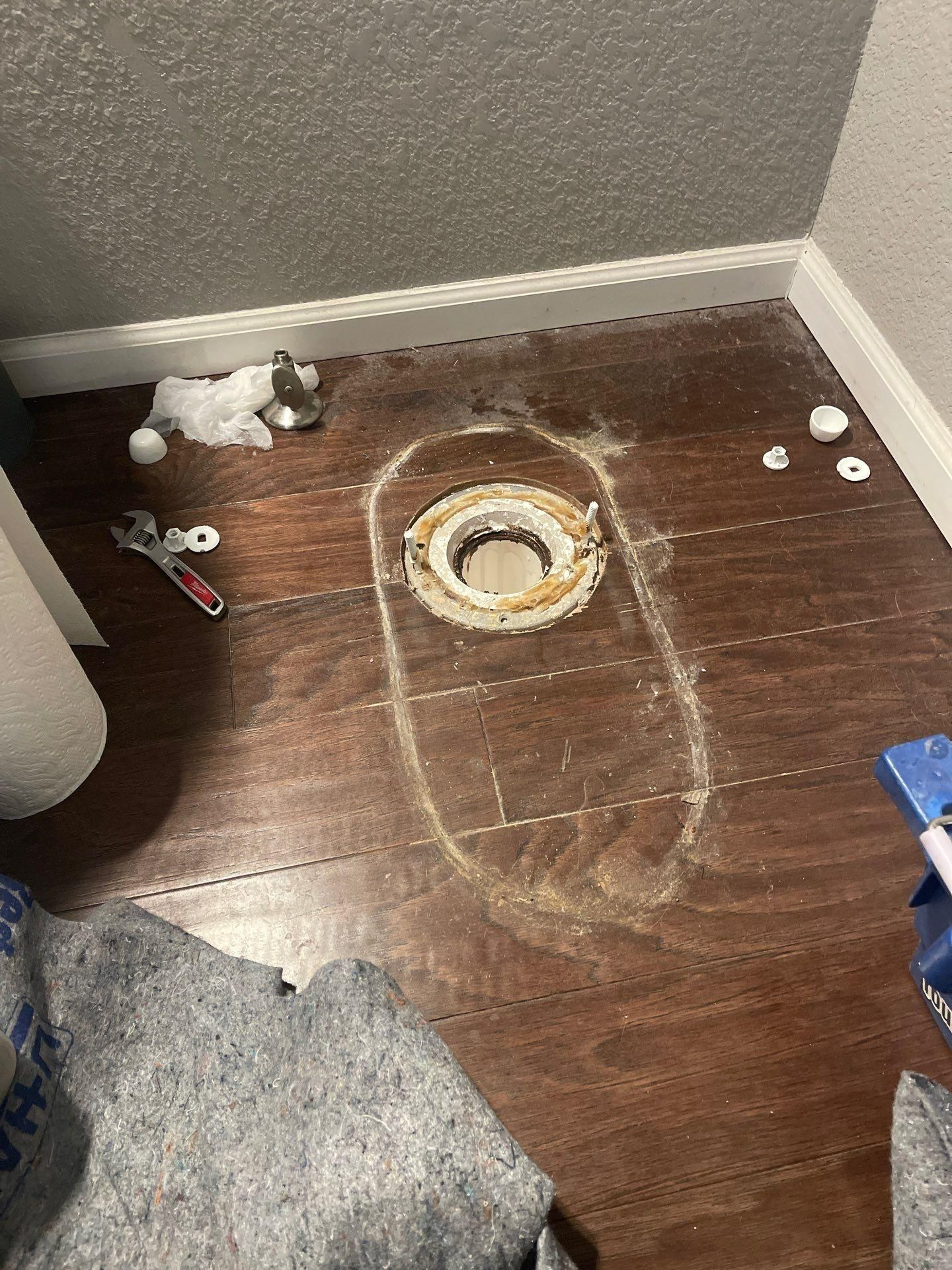 Bathroom floor with exposed toilet flange and chalk outline marking a repair area.
